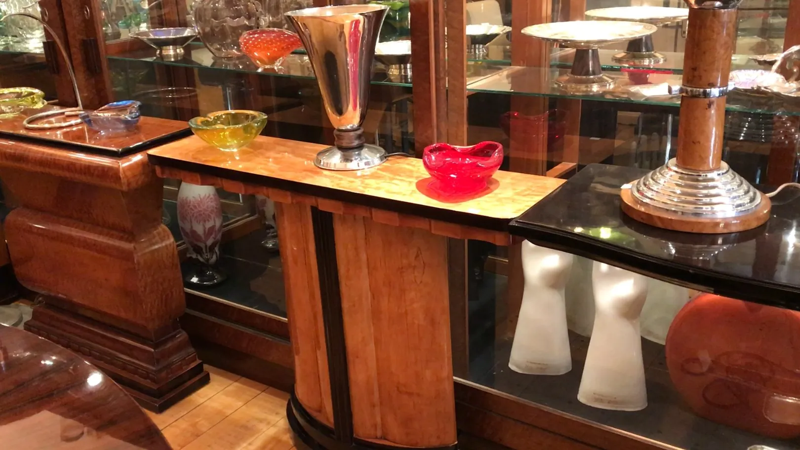 Una lámpara de mesa antigua con base de diseño elegante, rodeada de objetos decorativos.