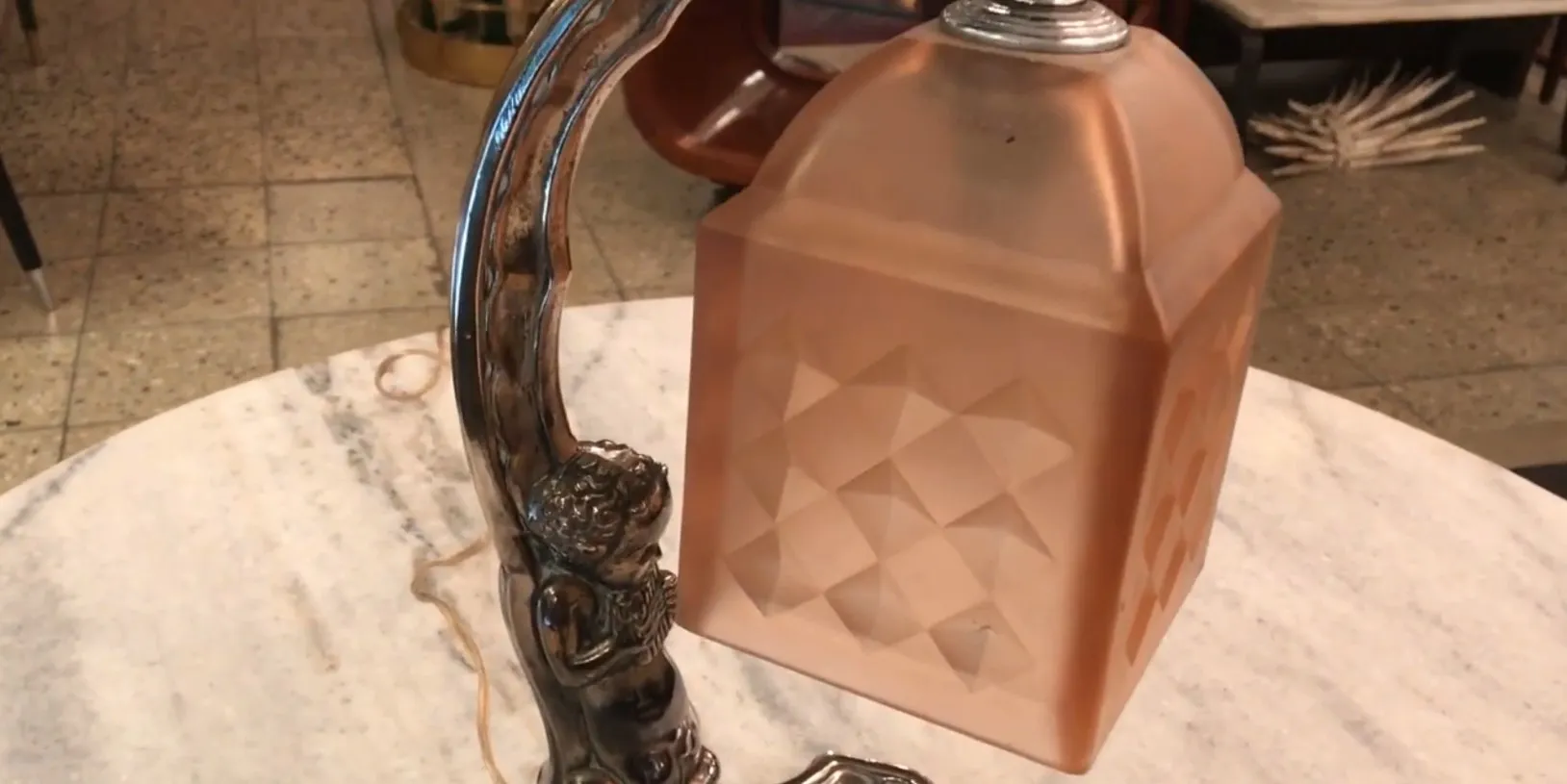 Lámpara de mesa antigua con base en forma de figura, luz suave.