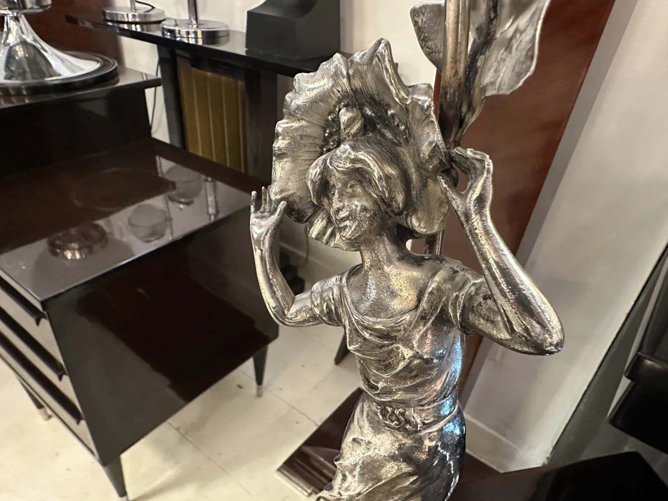 Antique table lamp with decorative figure, art deco style against an elegant backdrop.