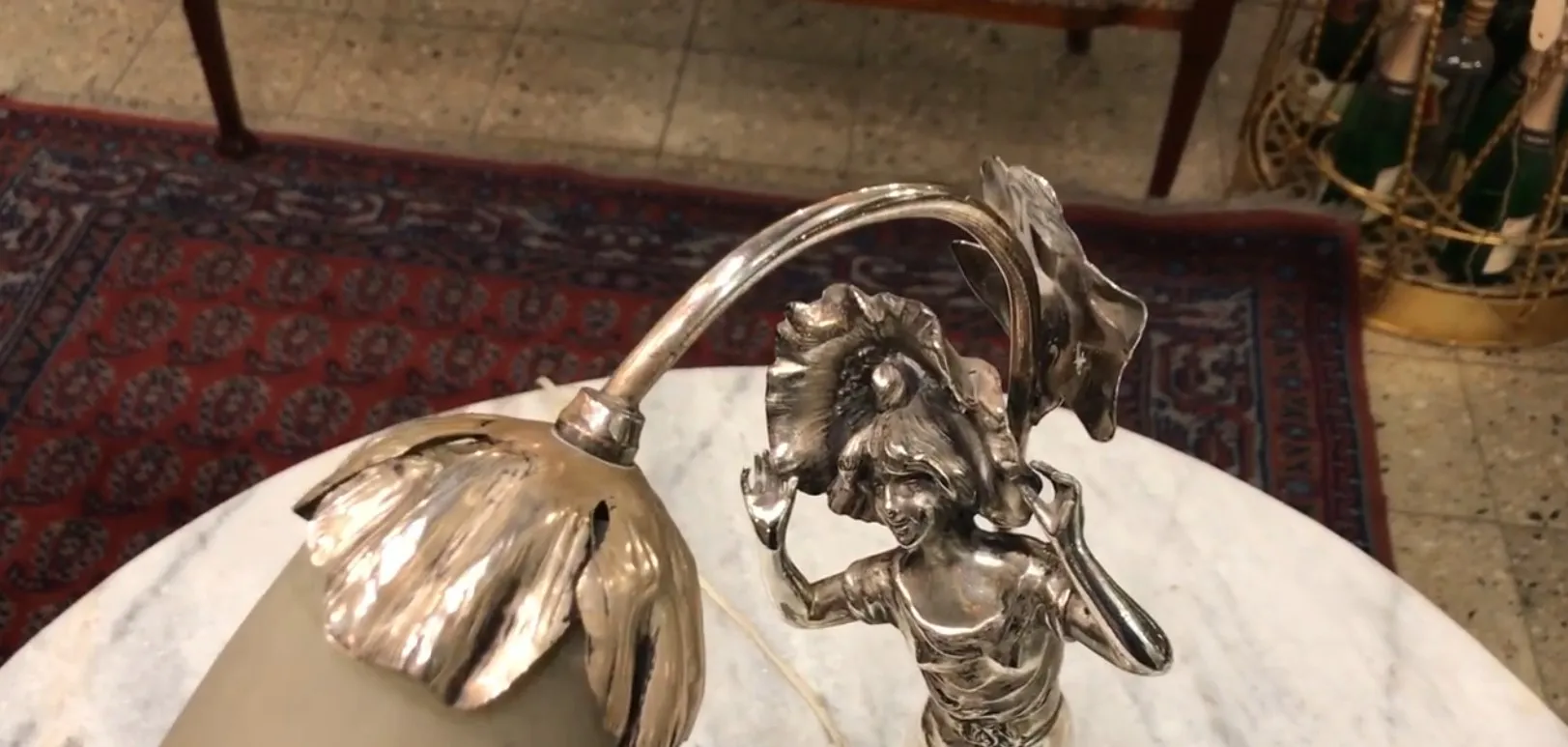 Details of an antique table lamp with a female figure and flower