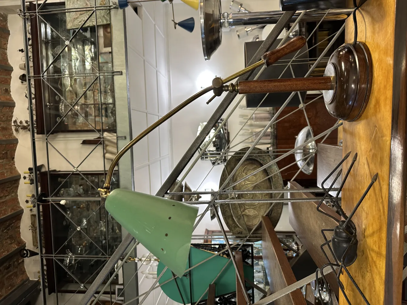 Ancienne lampe de bureau verte, avec base en bois et bras réglable, dans un environnement vintage.