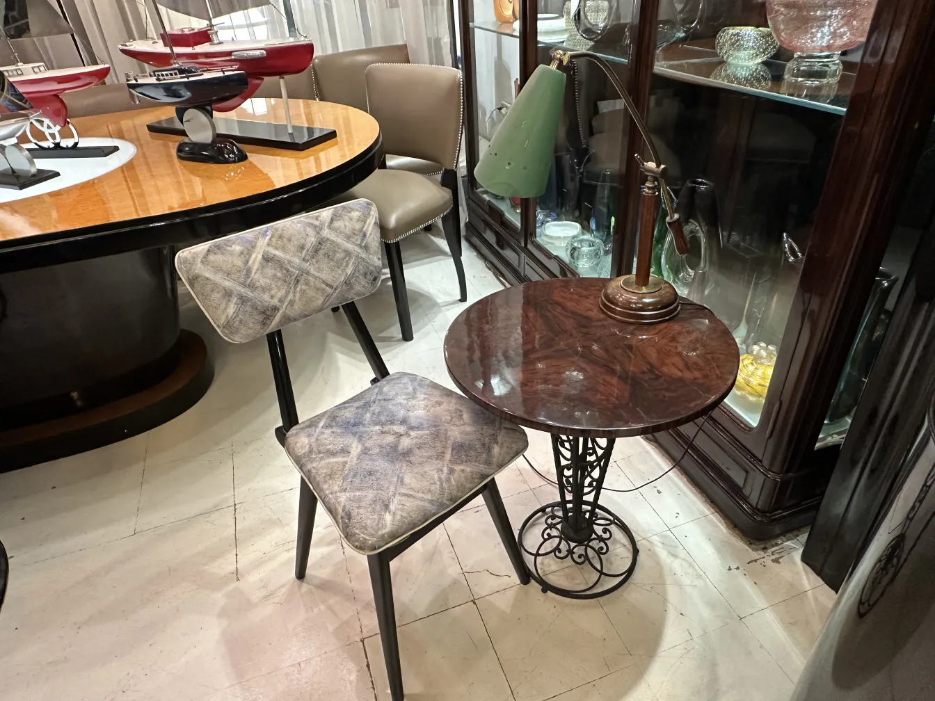 lampe de bureau ancienne avec un abat-jour vert et un pied en laiton, entourée de chaises et de tables dans un cadre chaleureux