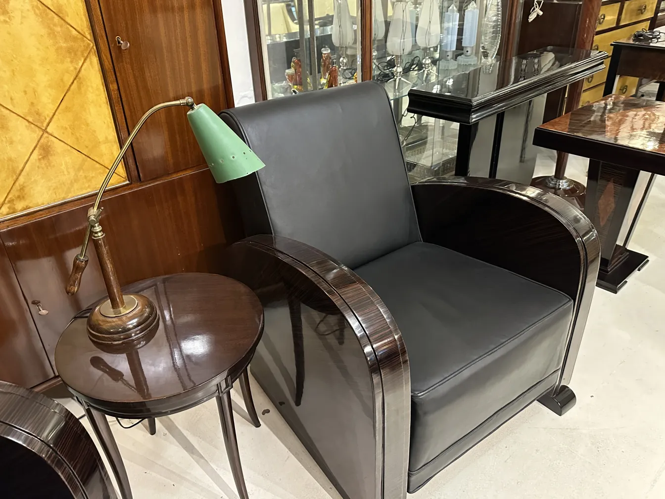 lámpara de mesa antigua con base de metal y pantalla verde, junto a sillón negro