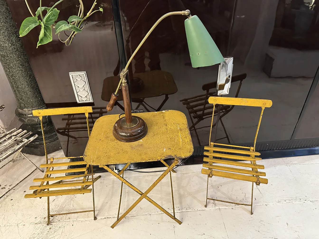 Antique table lamp with brown base and green shade, next to yellow chairs