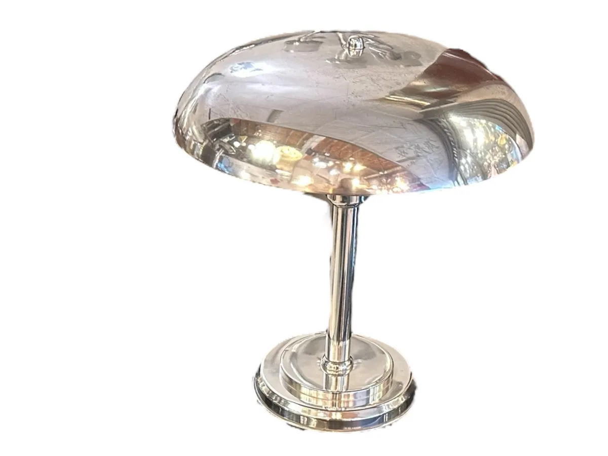 Eine antike Tischlampe mit glänzendem Fuß und runder Form, die sanft eine gemütliche Atmosphäre erhellt.