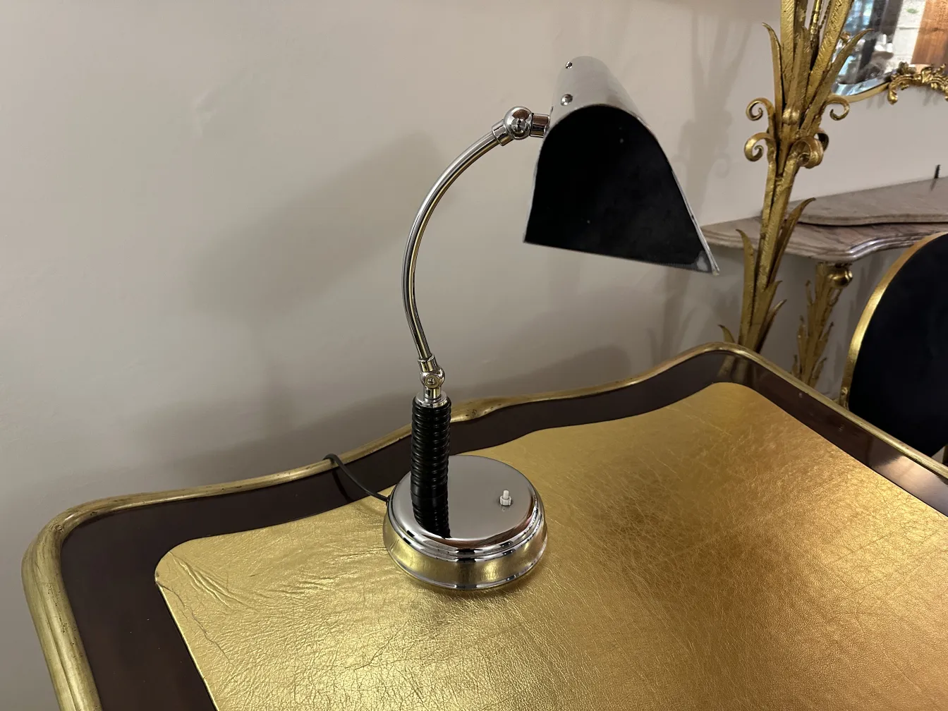 Lámpara de mesa antigua con base pulida, diseño elegante, ambiente sofisticado, sobre superficie dorada.