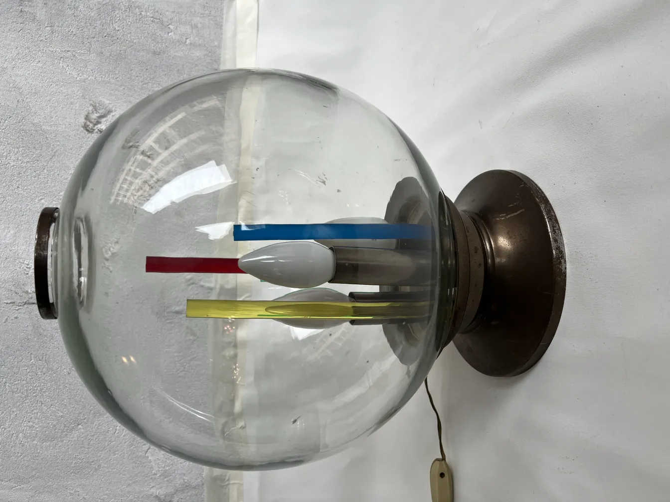 Antique table lamp with a round shape featuring blue, red, yellow, and white elements in a minimalist setting.