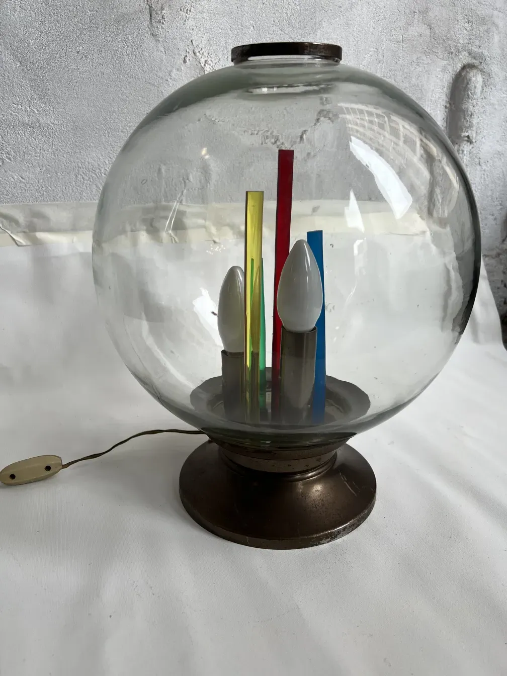 Lampada da tavolo antica con base rotonda e elementi colorati all'interno.