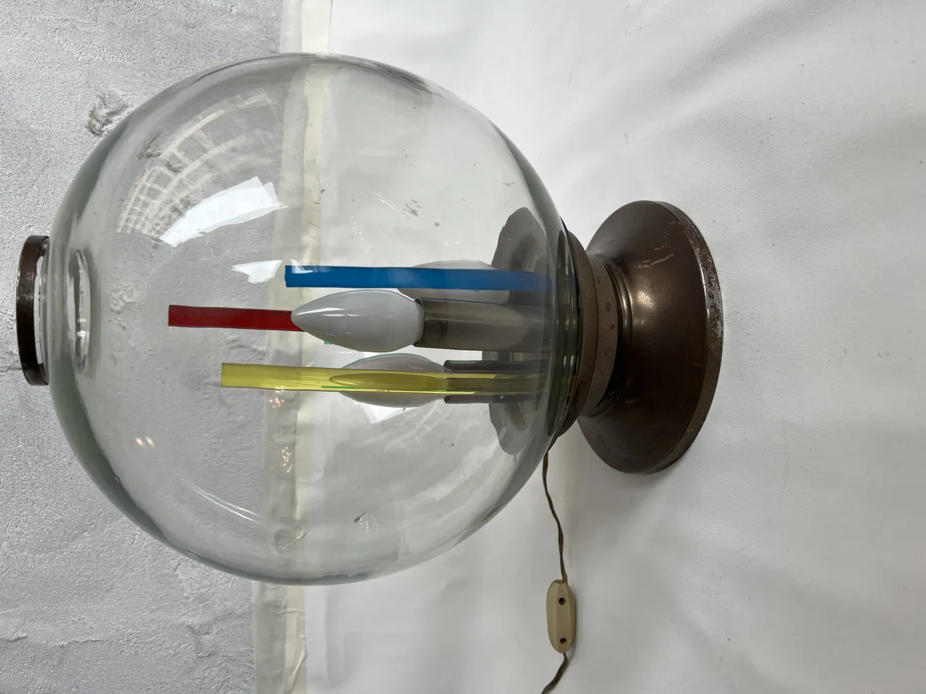 Antike Tischlampe mit Metallbasis und buntem Licht im Inneren.