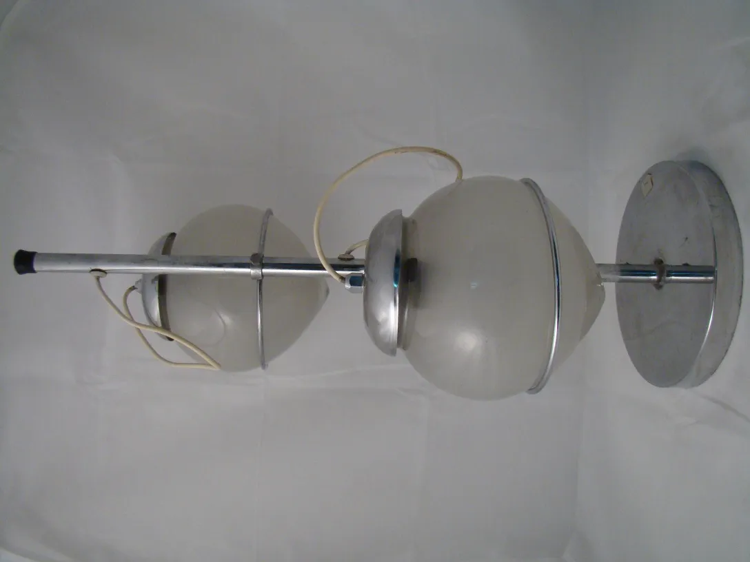 Lampada de mesa antiga com luz suave e esfera opalina em um ambiente minimalista.