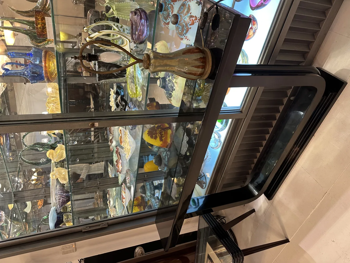 Lampada da tavolo antica decorativa con design classico in un ambiente elegante circondata da reperti in vetro.