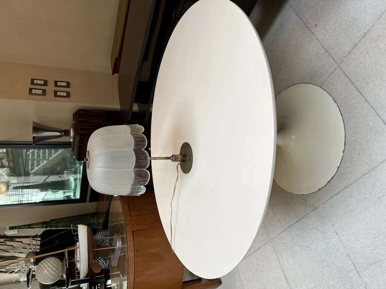 Lampada da tavolo antica con paralume bianco in un contesto moderno. Mobili contemporanei sullo sfondo.