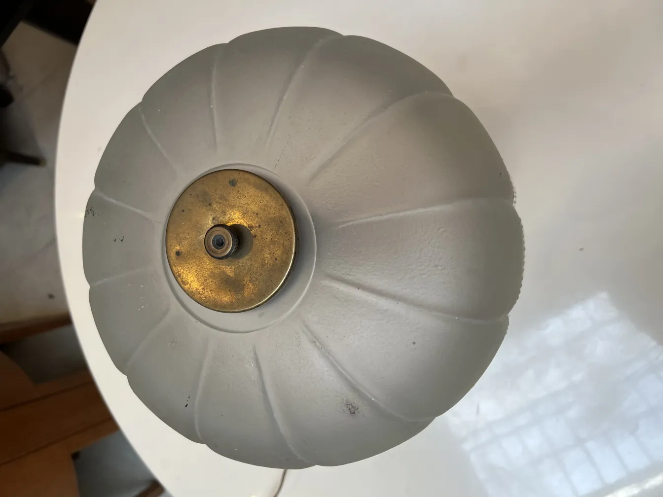 Antike Tischlampe mit rundem Schirm und goldenem Fuß in einer gemütlichen Umgebung.