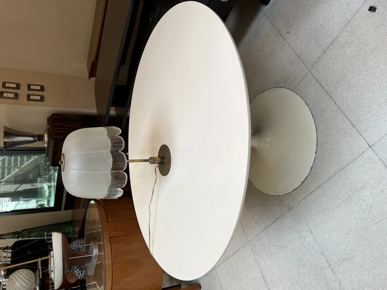 Antike Tischlampe mit weißem Schirm und runder Basis, in einem eleganten Umfeld.