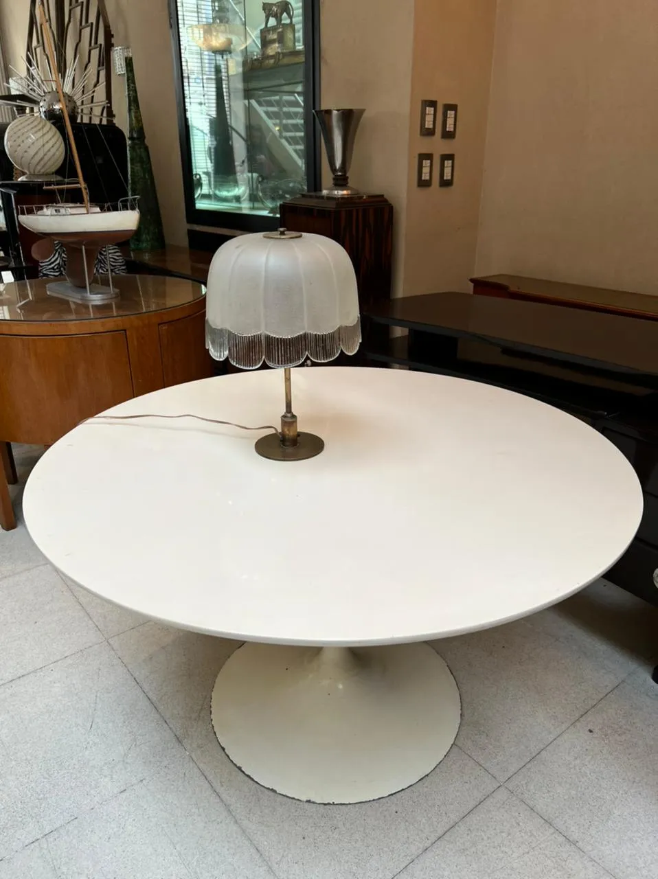 antike Tischlampe mit weißem Schirm auf einem runden weißen Tisch, sanfte Beleuchtung in einem antiken Raum