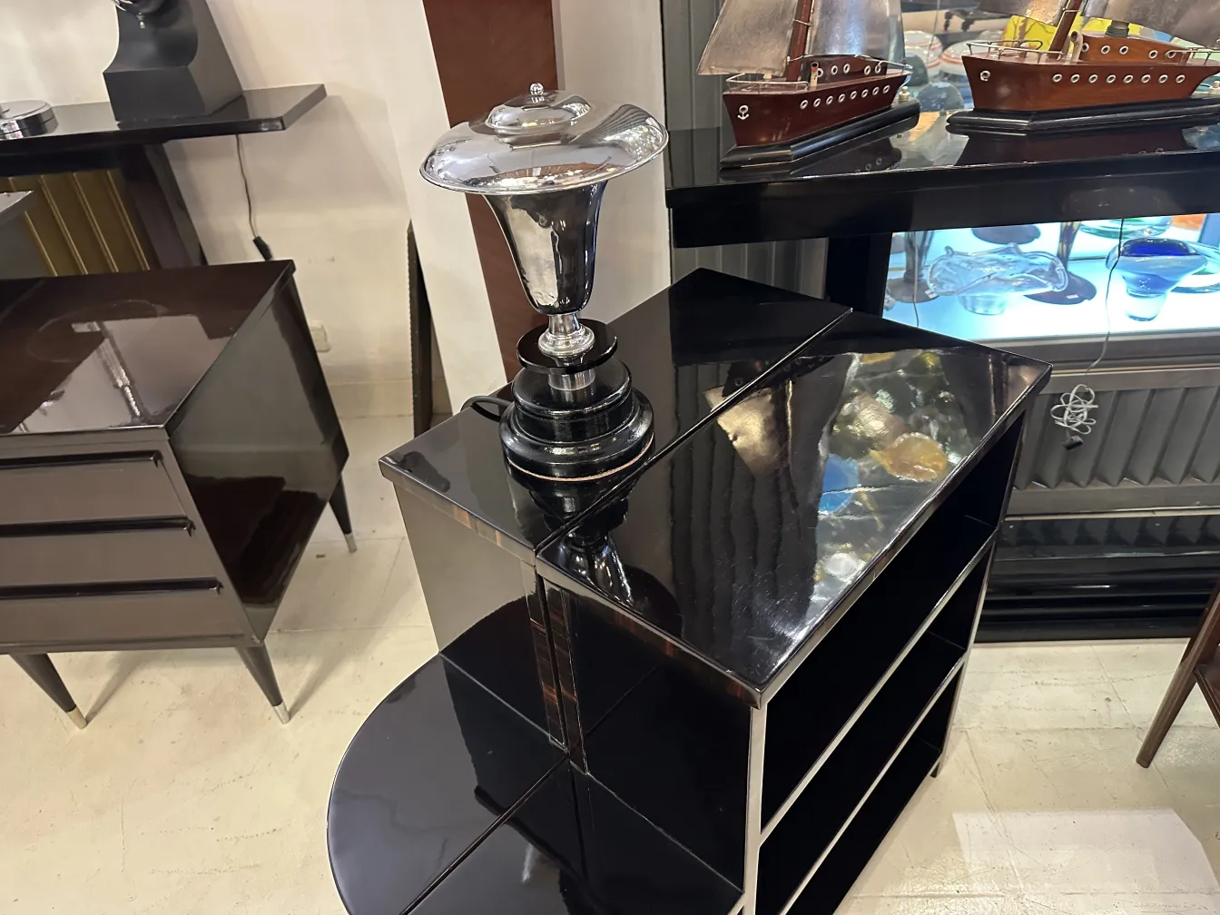 Lampada da tavolo antica con base nera e dettagli lucidi, in un ambiente di antiquariato.