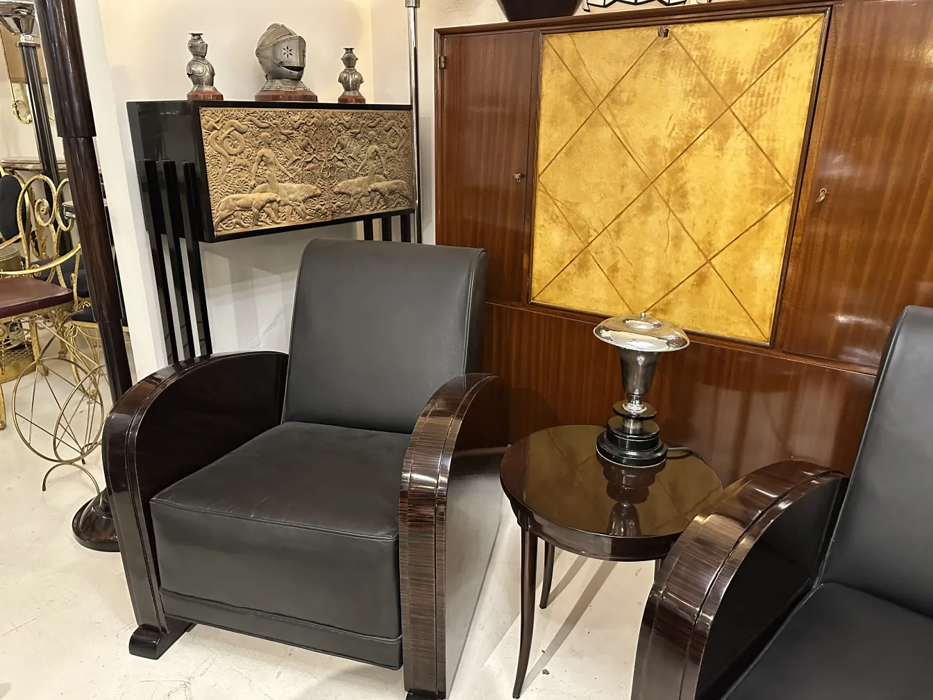 lampara de mesa antigua con base de color negro y detalles en la parte superior, junto a sillones