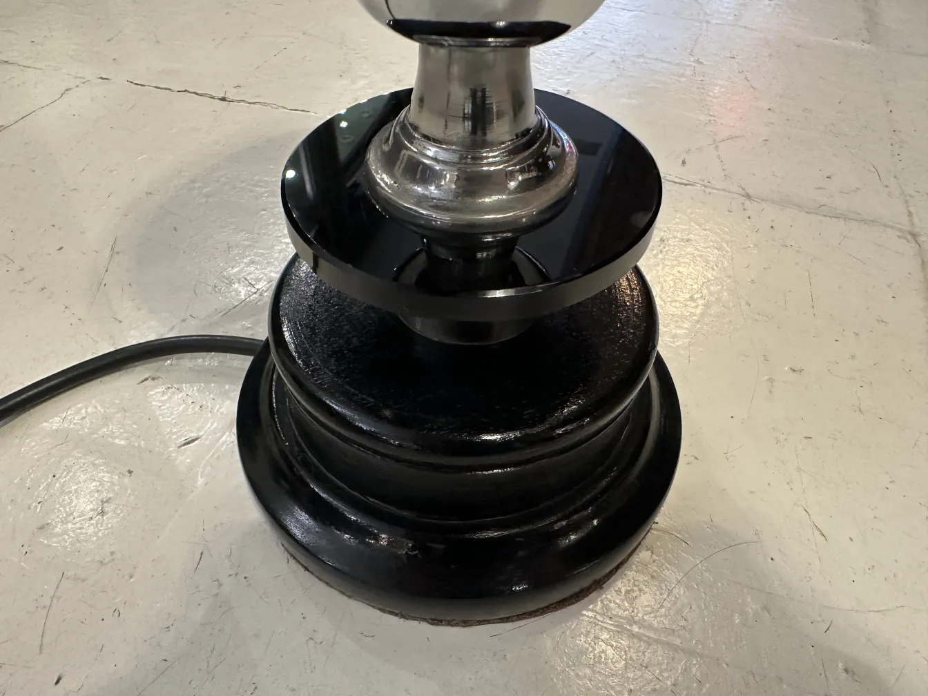 Lampada da tavolo antica con base nera lucida in un ambiente semplice.