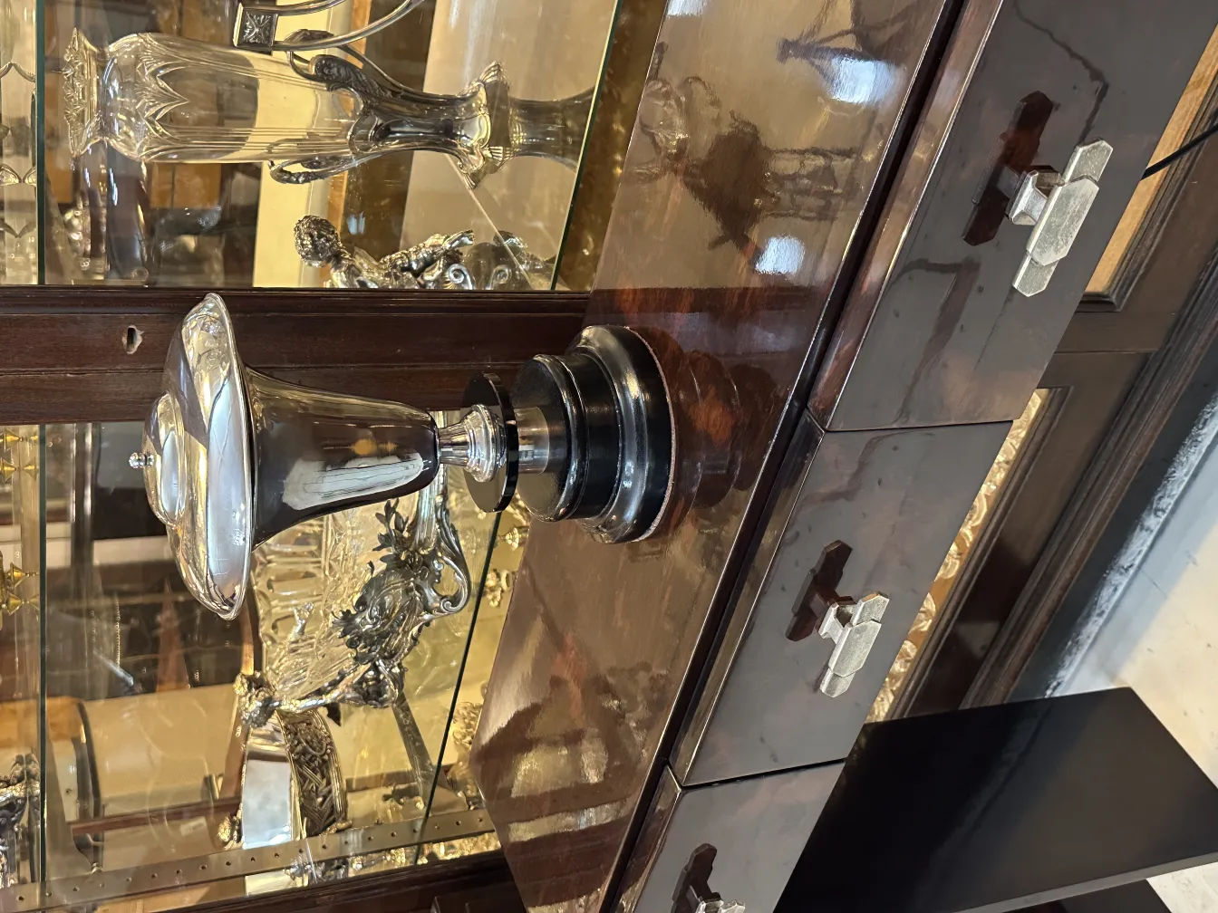 Antike Tischlampe mit glänzendem, elegantem Design, umgeben von anderen dekorativen Objekten.