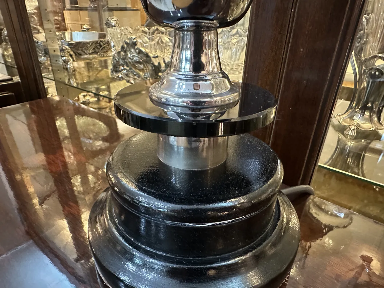 Lámpara de mesa antigua con base negra y detalles brillantes en un ambiente elegante.