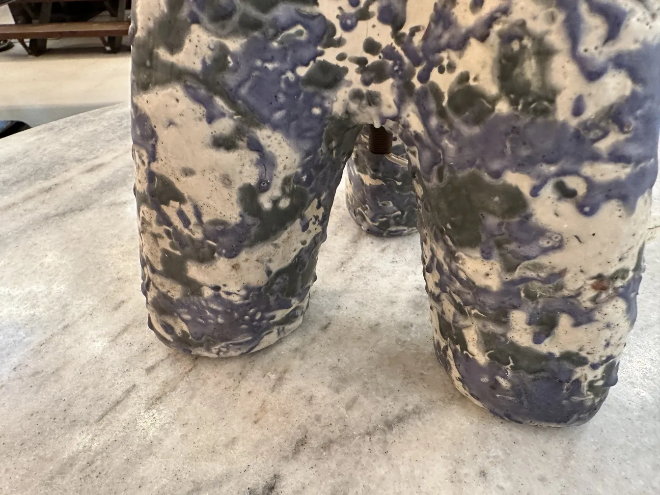 불규칙한 형태와 부드러운 색상으로 된 앤틱 테이블 램프가 대리석 테이블 위에 있습니다