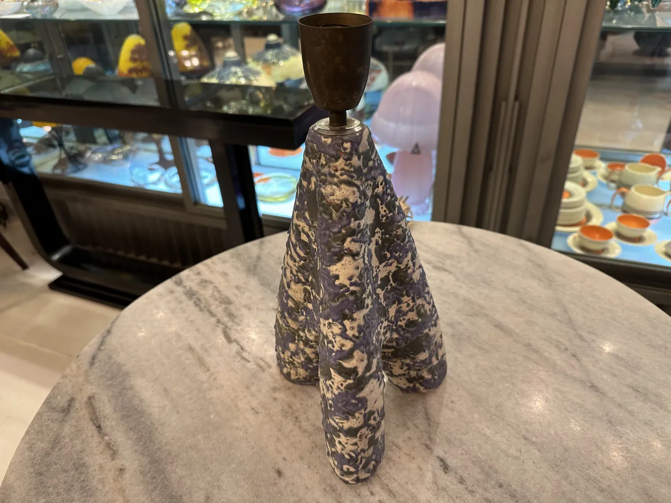 lampada da tavolo antica con base decorativa in ceramica, in un ambiente elegante con oggetti in vetro sullo sfondo