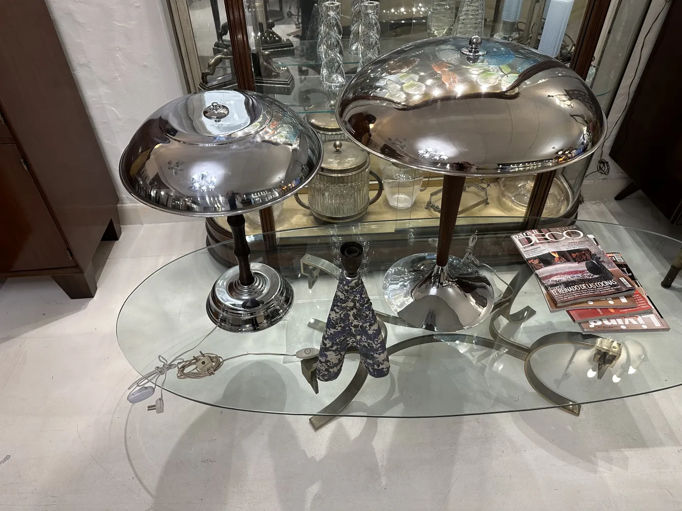 Antigua lámpara de mesa con base brillante, estilo clásico, sobre mesa de cristal.