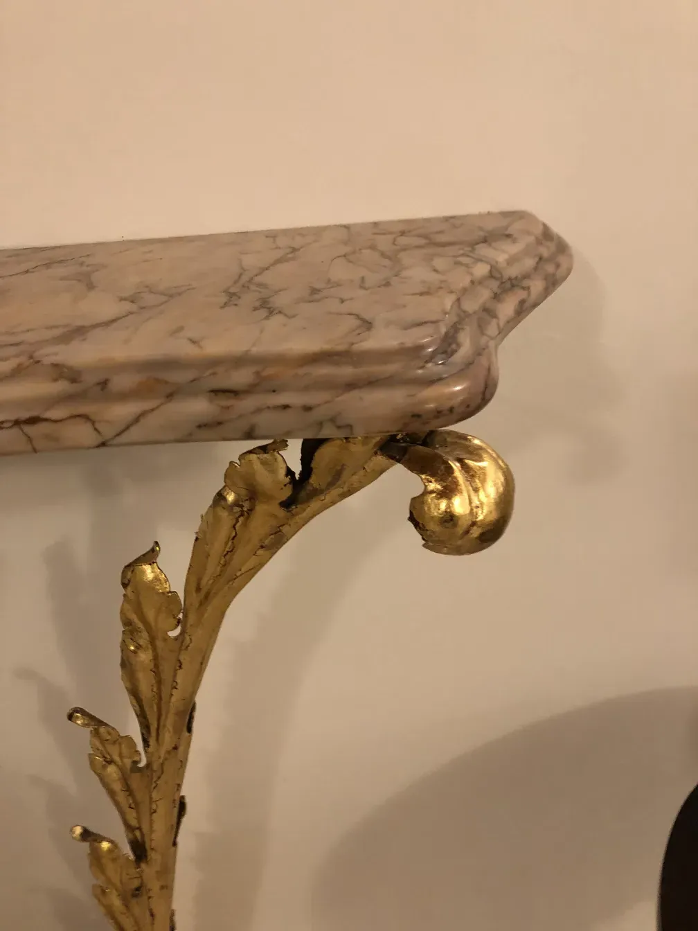 View of the decoration on an antique console, featuring golden details and an elegant design on a light surface.