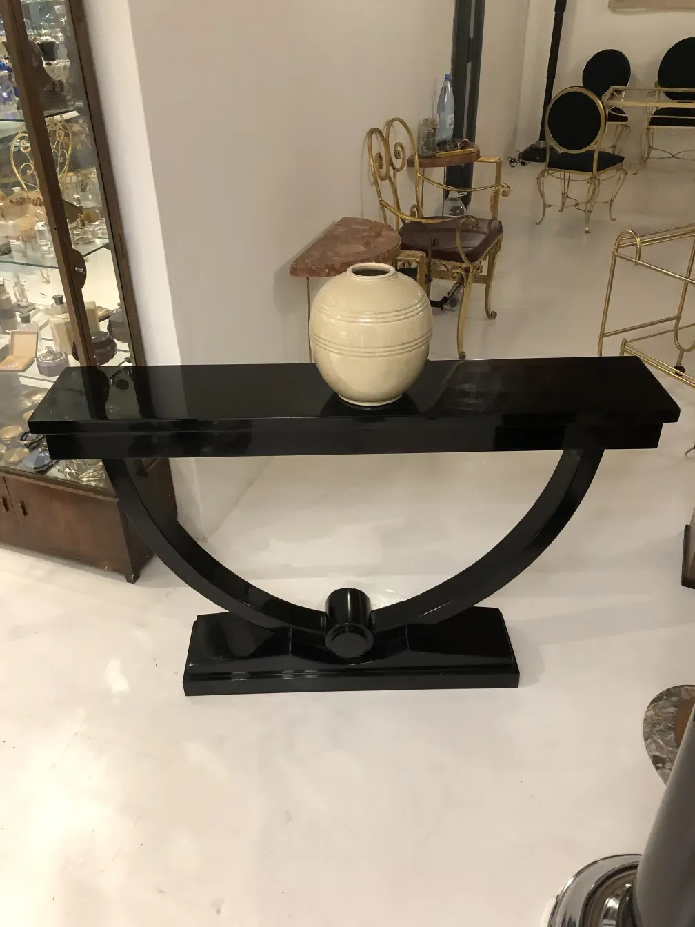 consola antigua decorativa negra con forma curva y jarrón blanco