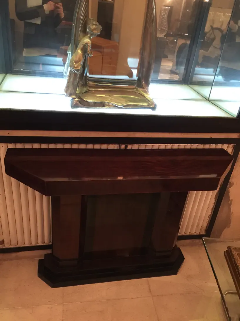 Antiga consola de armazenamento com vidro, elegante e clássica. Destaca um fundo iluminado e itens decorativos.