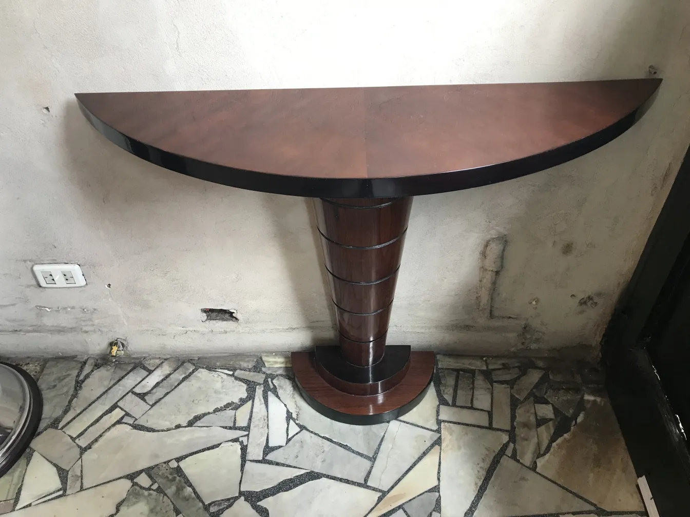 una antigua consola con forma semicircular y base elegante en un ambiente neutro