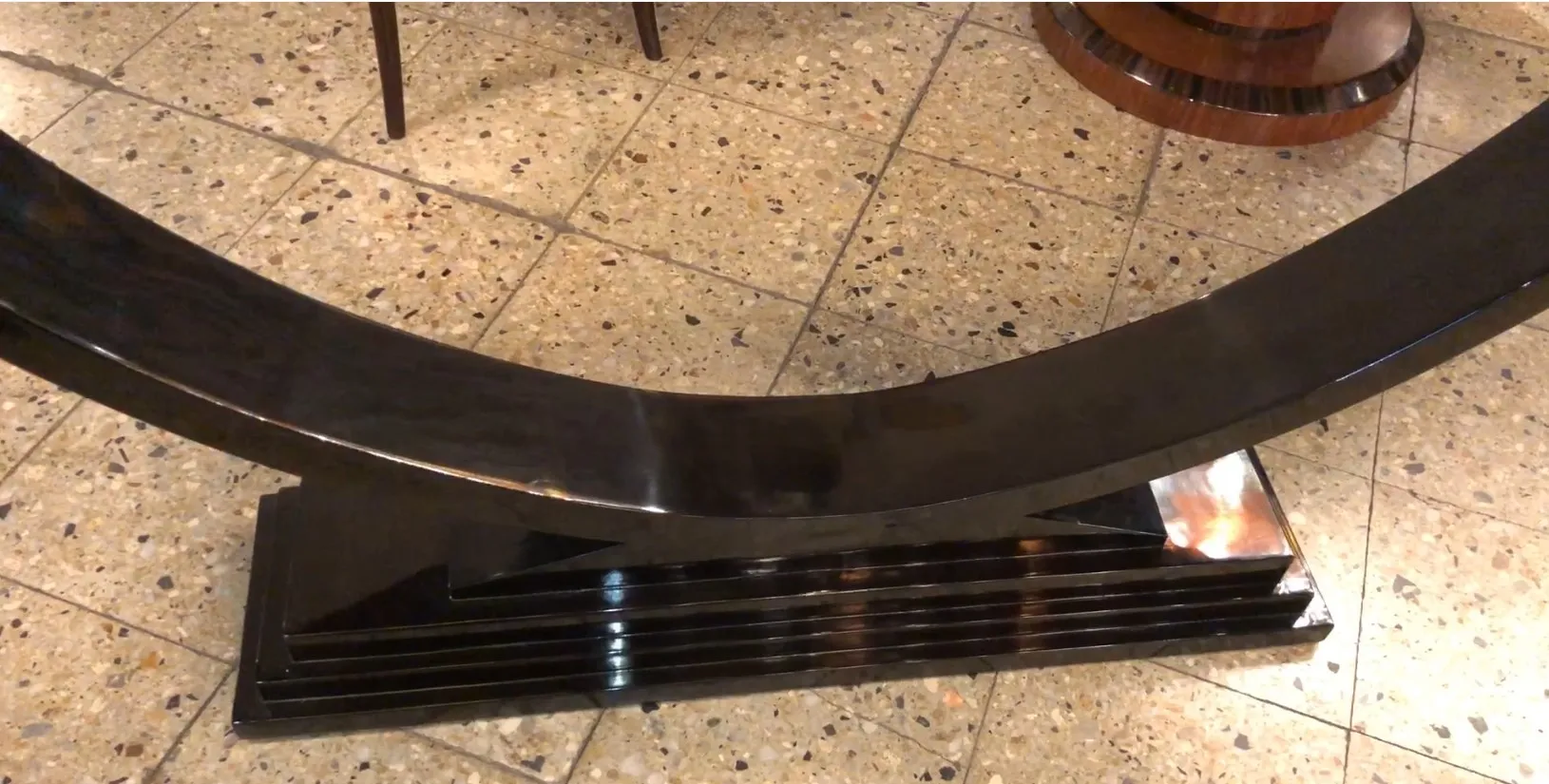 装飾的な石の床の上にある古い黒いコンソールテーブル