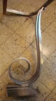 Vista di una gamba di console antica con una forma elaborata in un ambiente neutro.