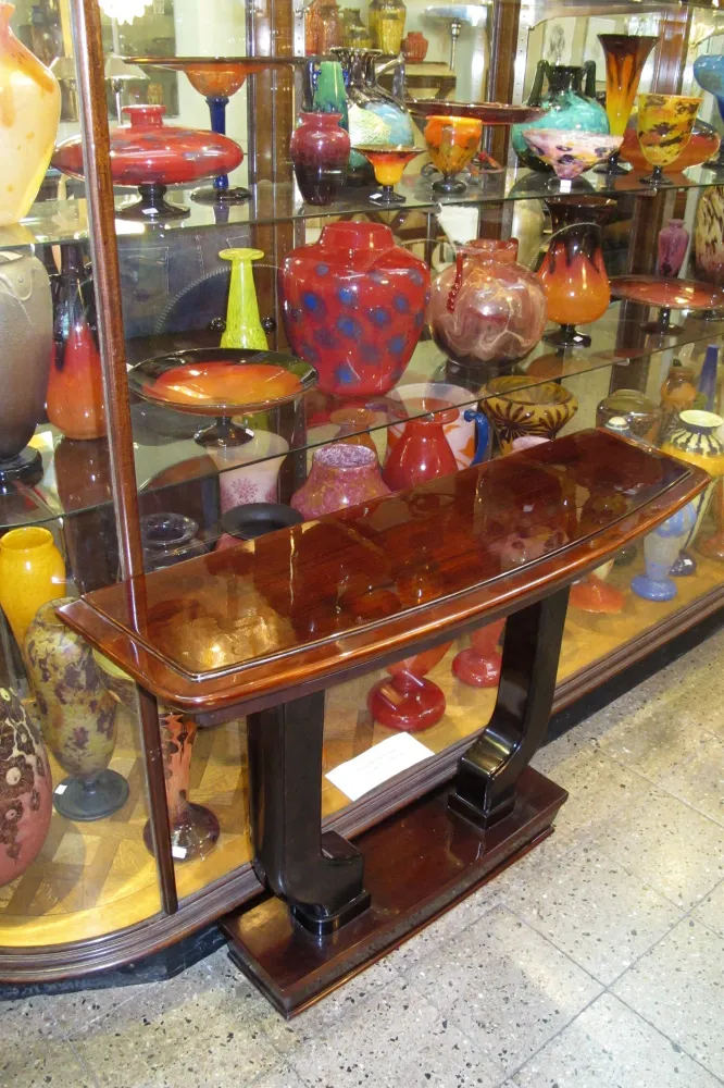 antique console with curved shape, background of decorated display cases