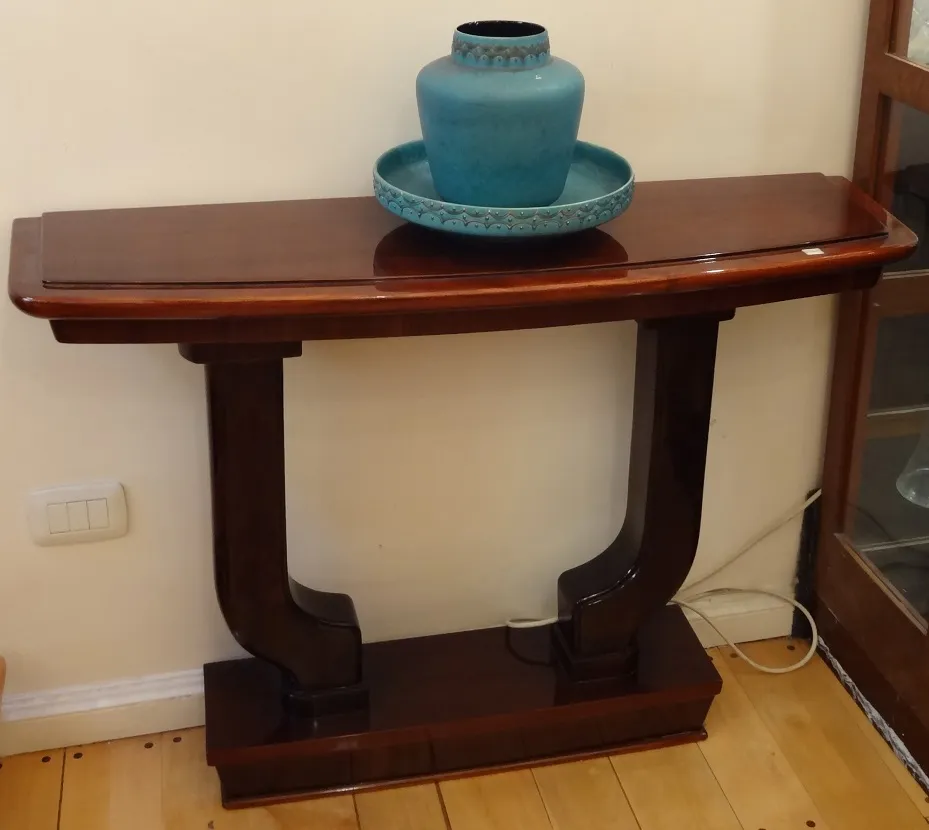 antigua consola con acabado brillante, decorada con un jarrón azul