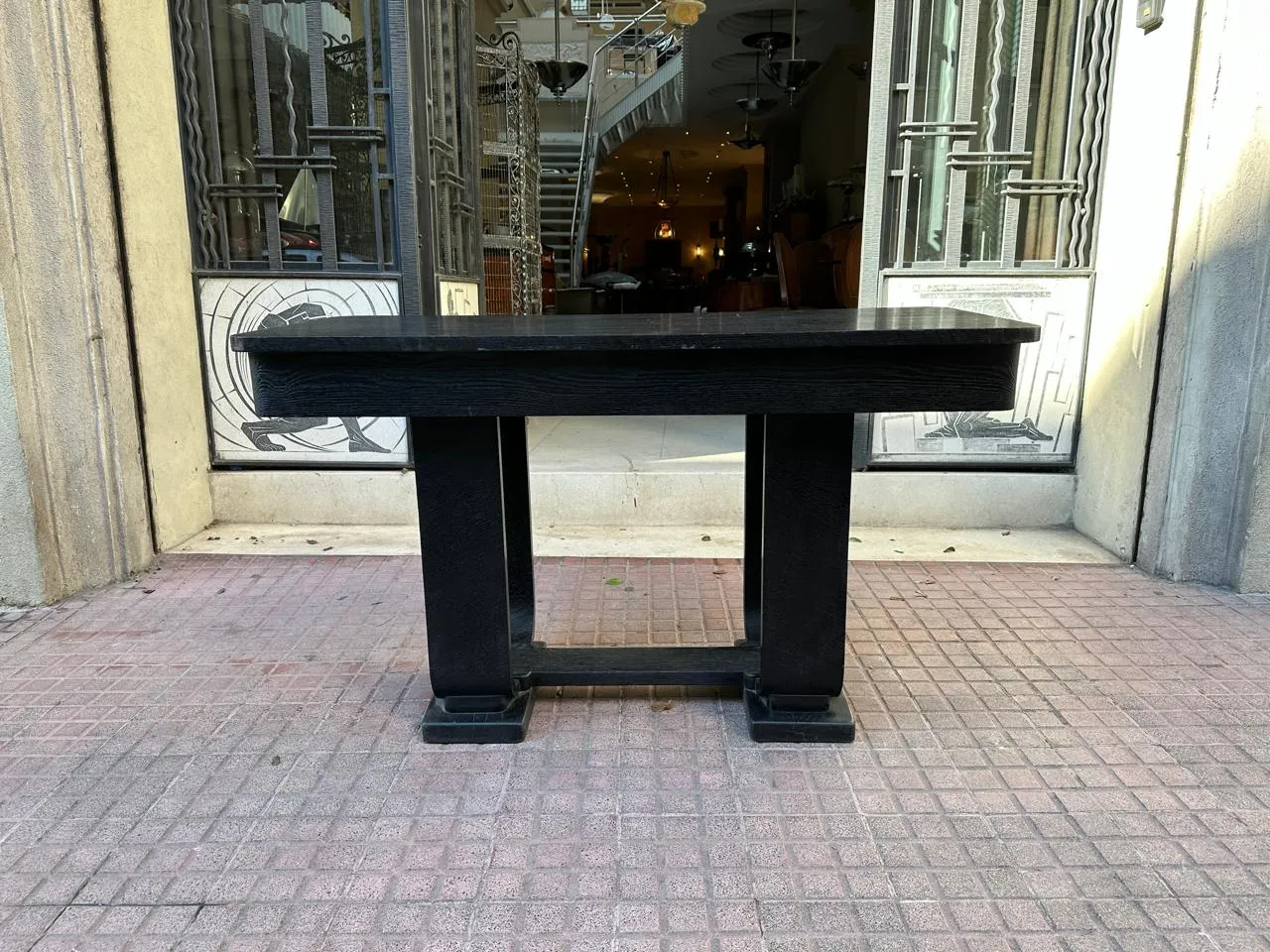 Ancienne console décorative noire devant des portes en verre