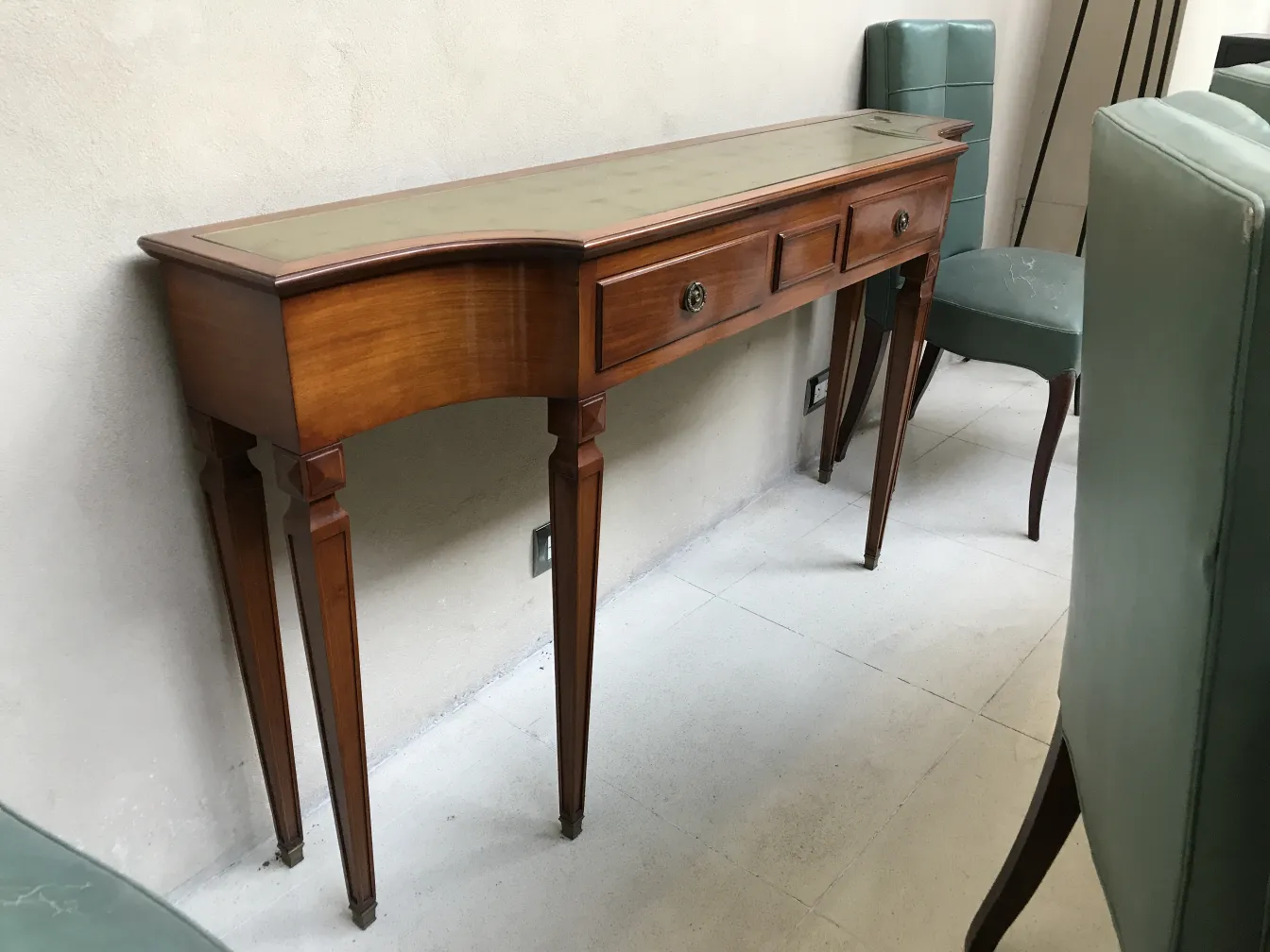 Consola antigua de estilo clásico con detalles decorativos, colocada en un ambiente elegante.