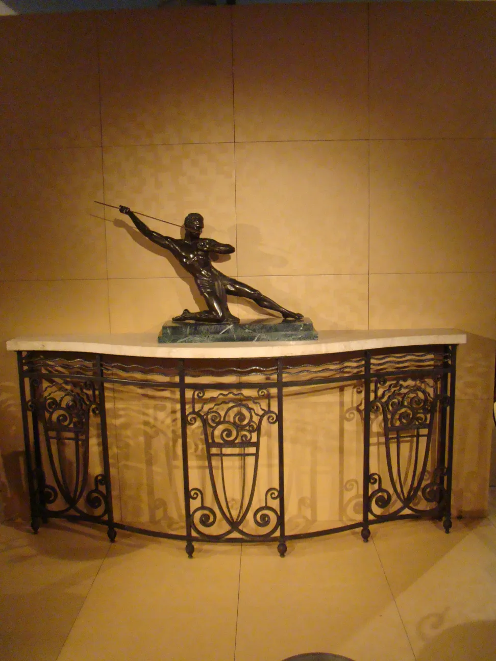 Antica consolle decorativa con scultura al centro, sfondo neutro.