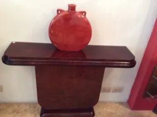 प्राचीन कंसोल टेबल पर सजावटी लाल बर्तन