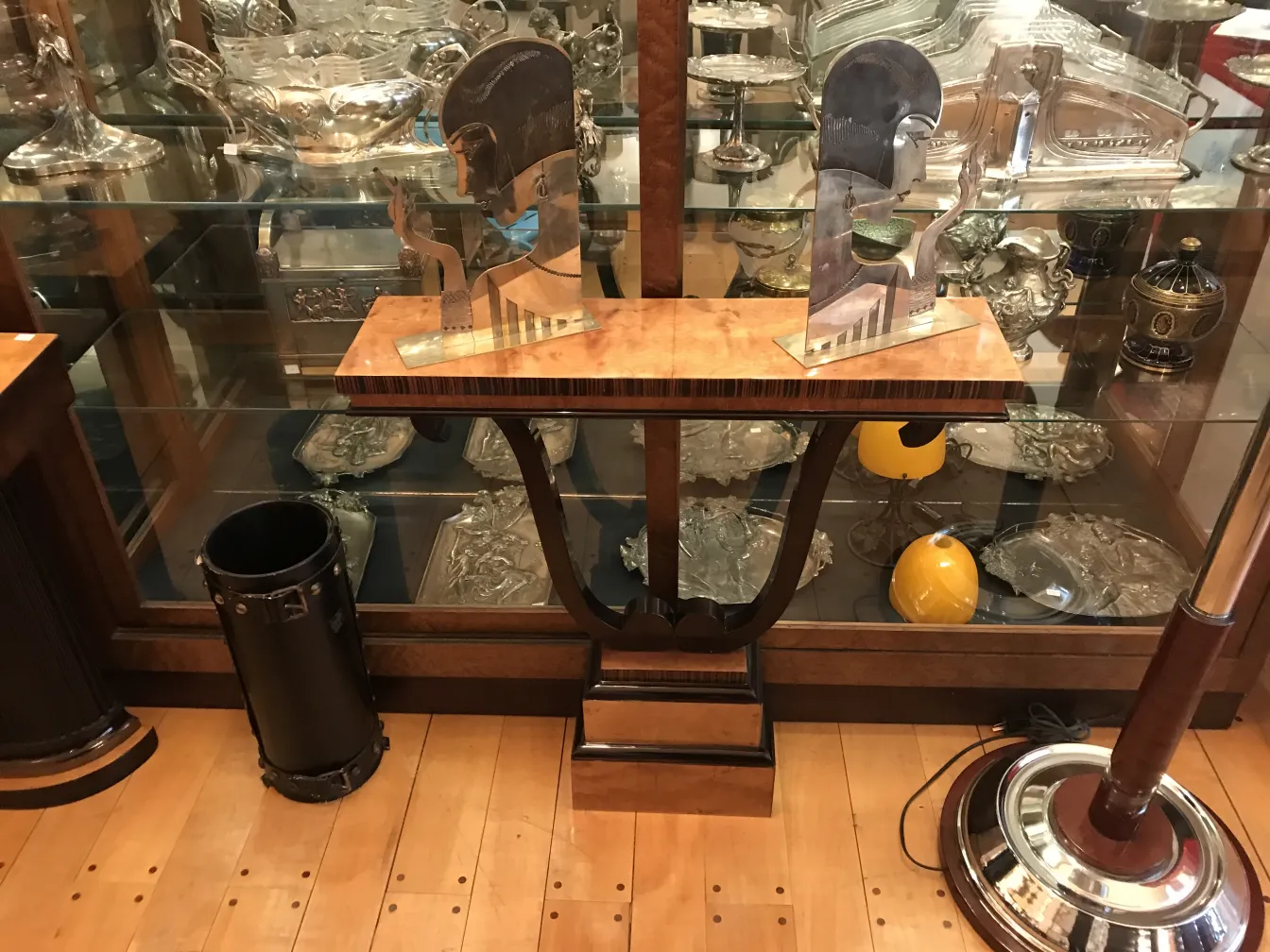 Vista de una antigua consola decorativa con elementos de cristal y metal alrededor, incluyendo una figura estilizada.