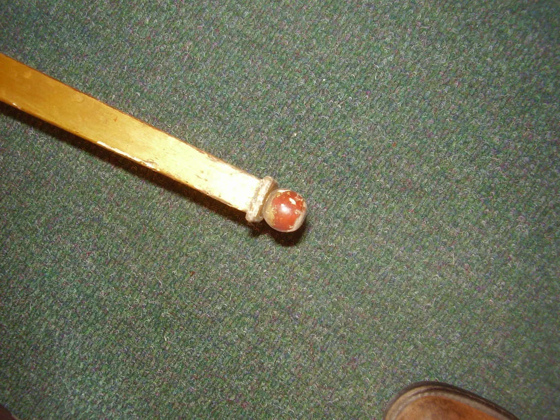 Detalle de una antigua consola decorativa con acabado dorado y esfera.