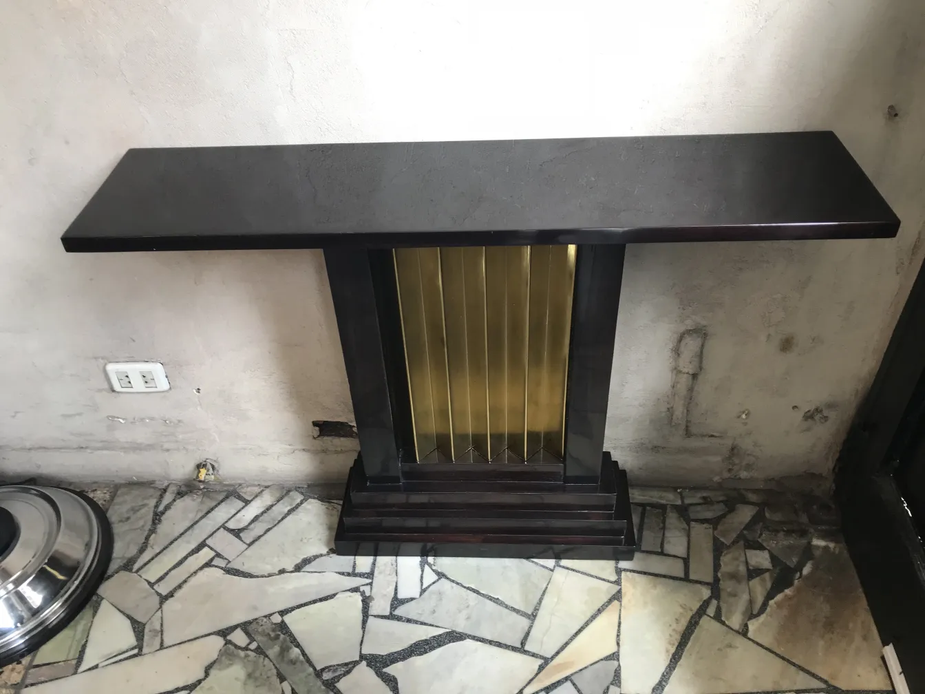 consolas antigas com superfície preta e pé dourado em um ambiente simples