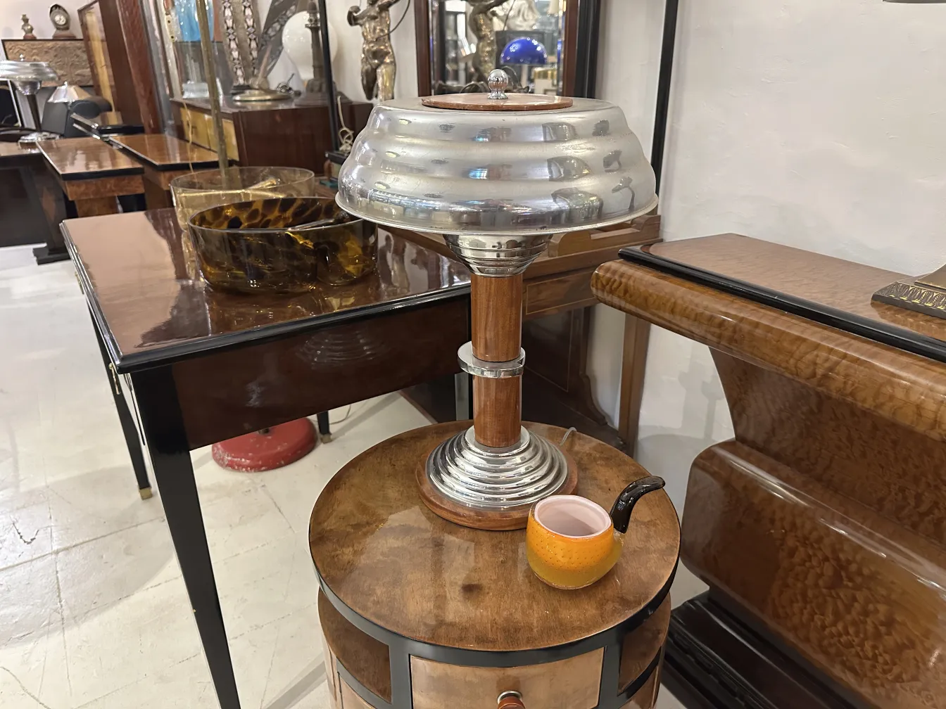 dos consolas antiguas con base circular y detalles dorados, en un ambiente de antigüedades