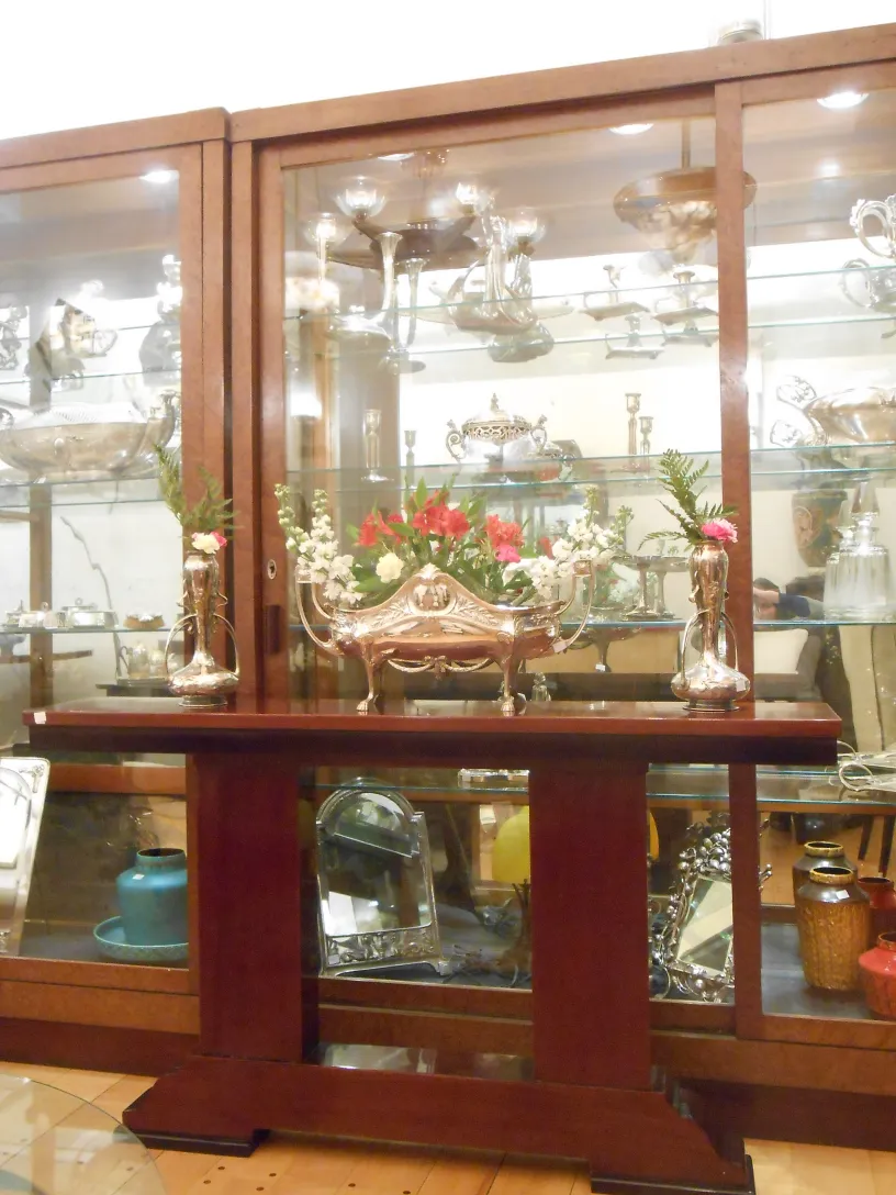 Três consolas antigas exibidas elegantemente, decoradas com flores.