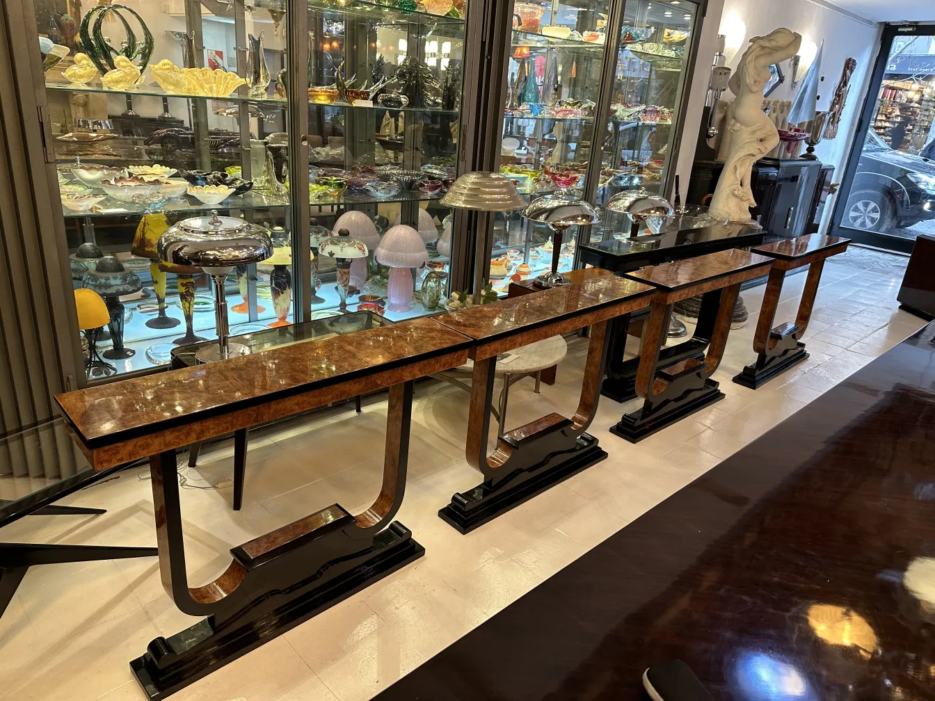 Detalhe de três consolas antigas em um ambiente decorativo com vários objetos.