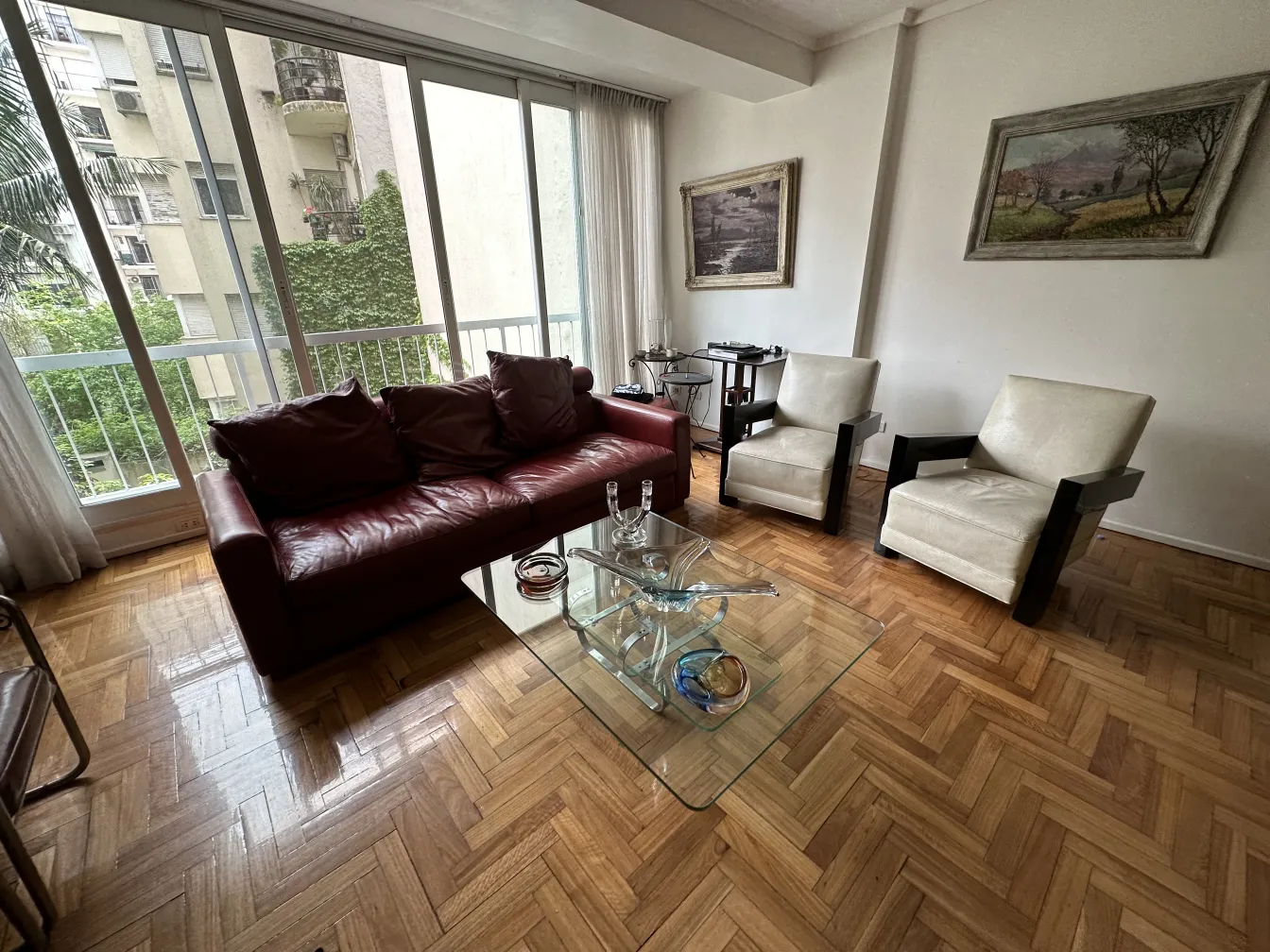 Antik dekorativer Kandelaber in einem modernen Wohnzimmer mit Stühlen und Glastisch.