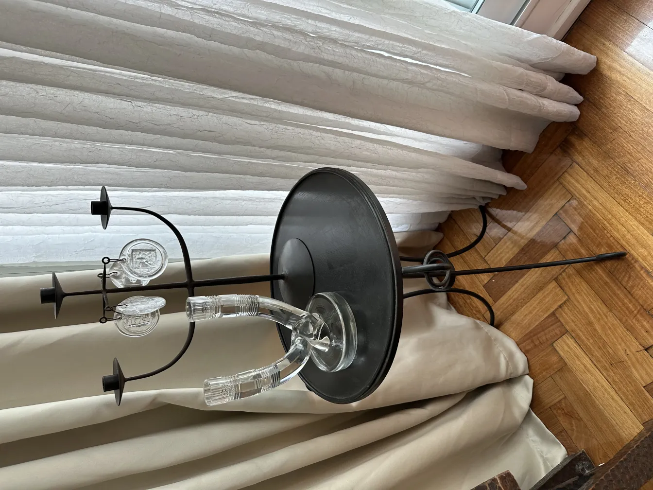 candelabro antico con tre bracci e un design elegante, posizionato su un tavolo accanto a tende bianche