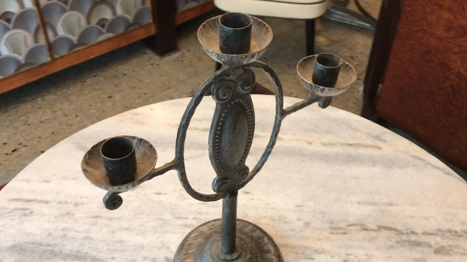 شمعدان قديم بثلاثة أذرع وقاعدة مزخرفة، موضوعة على طاولة. خلفية مريحة.