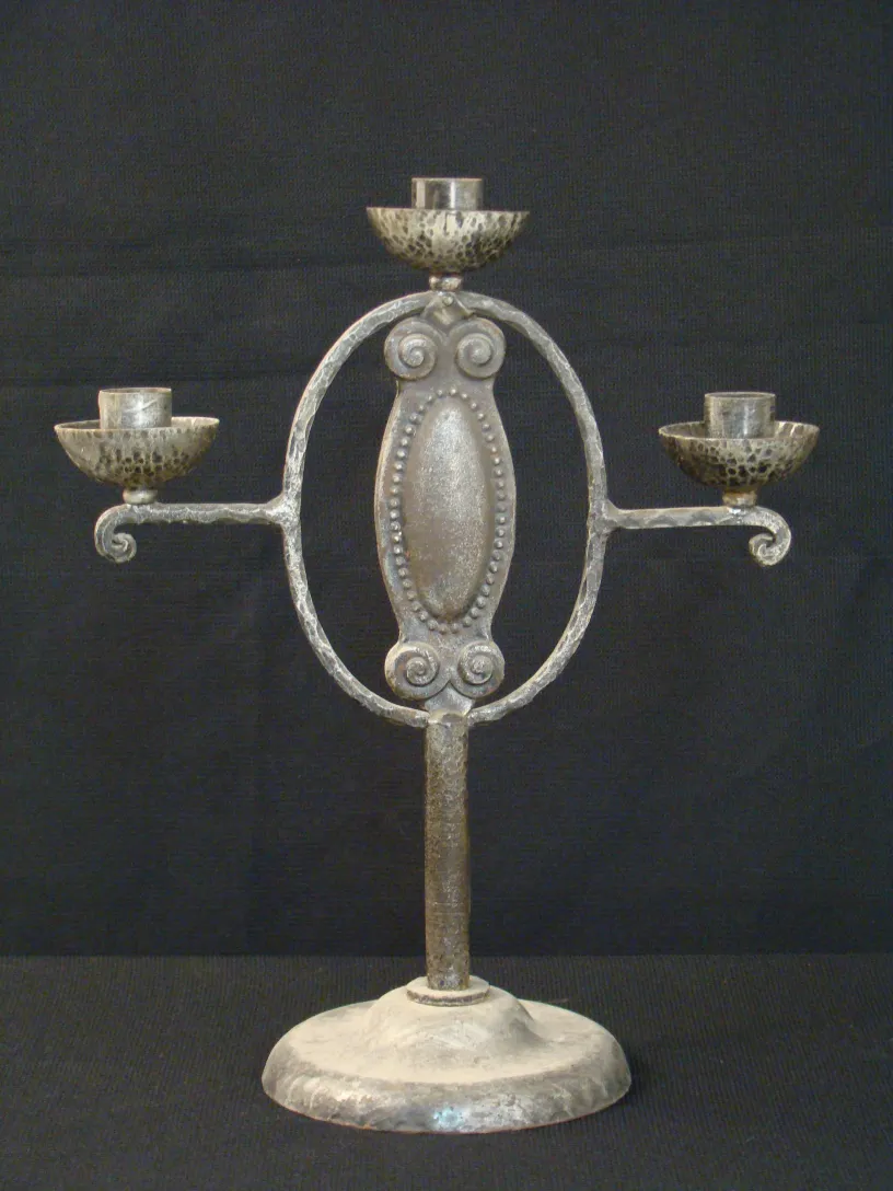 Candelabro antiguo con tres brazos y base redonda.