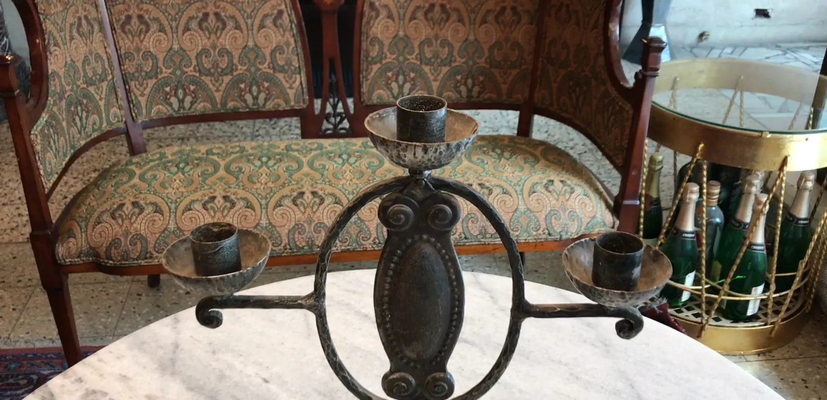 candelabre ancien avec trois bras et base ornée, fond avec meubles anciens